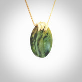 This piece is a medium sized cupped disc pendant. It was carved for us by Ric Moor from a lovely deep and milky green piece of New Zealand flower jade. It is suspended on a beige coloured braided cord that is length adjustable.